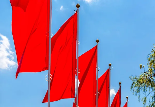 Czerwone flagi macha na tle niebieskiego nieba — Zdjęcie stockowe