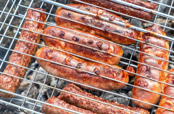 Saucisses appétissantes de viande sur une grille métallique — Photo