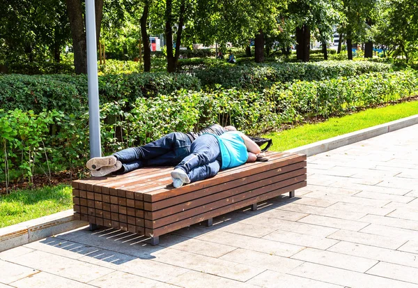 Bezdomovci spí na dřevěné lavičce — Stock fotografie