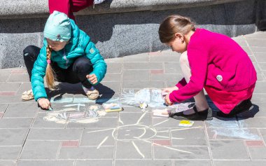Genç kızlar kaldırıma tebeşirle çizerler.