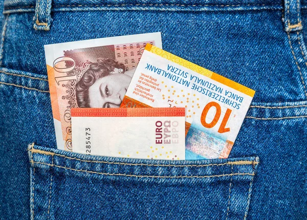 Banknotes of England pound, Swiss franc and Euro sticking out of the back jeans pocket