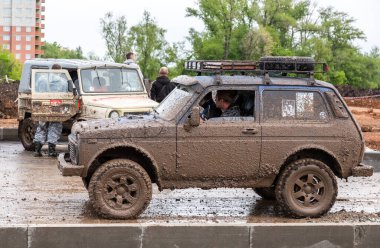 Samara, Russia - May 28, 2017: Off-road vehicle Lada 4x4 after driving in the rain on extremely dirty rural road clipart