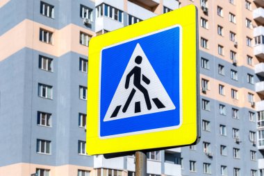 Bir apartmanın arka planında yaya geçidi trafik işareti var.