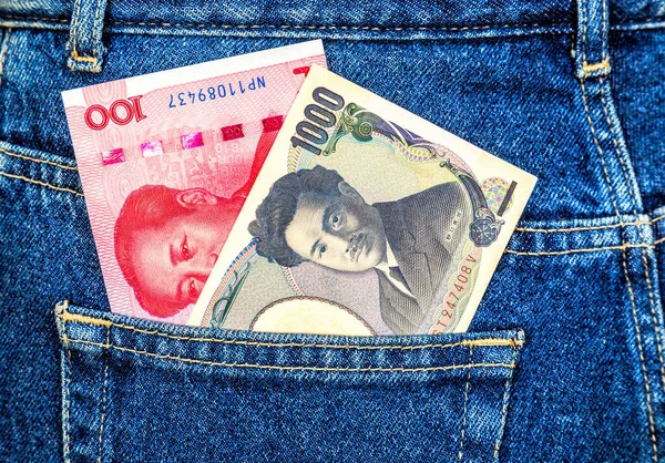 日本円と中国元の紙幣の裏側のジーンズのポケットから突き出た — ストック写真