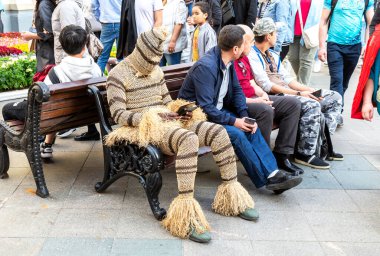 Moskova, Rusya - 7 Temmuz 2019: Koruyucu karnaval kıyafeti giymiş bir adam bankta oturuyor