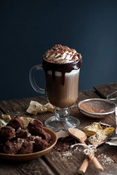 Kopi dengan krim dan truffle ceroboh di meja kayu tua — Stok Foto