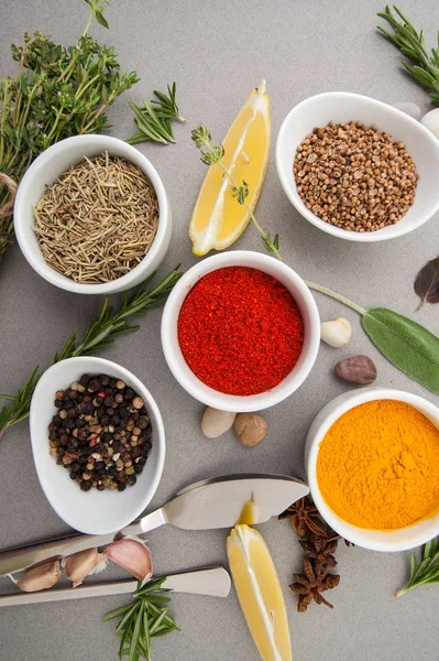 Vários secados e temperos e seasonings frescos em uma mesa cinza — Fotografia de Stock