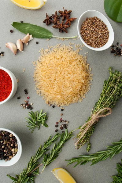 Arroz, hierbas especiadas y especias en una mesa de piedra gris claro —  Fotos de Stock