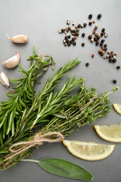 Hierbas picantes frescas y una mezcla de pimientos en una mesa de piedra gris —  Fotos de Stock