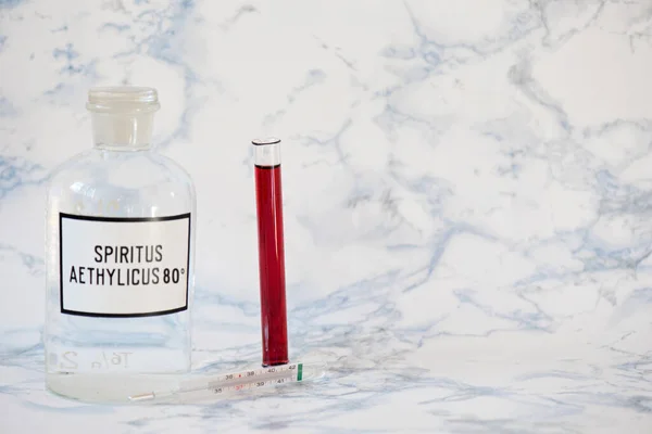 Ethanol in a bottle and blood analysis Tablet in the fingers of hand — Stock Photo, Image