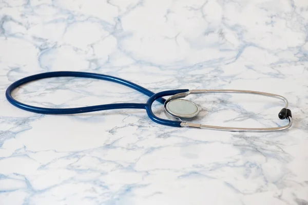 Medicinskt stetoskop eller fonendoskop över ljusblå bakgrund Tablet i fingrarna på handen — Stockfoto