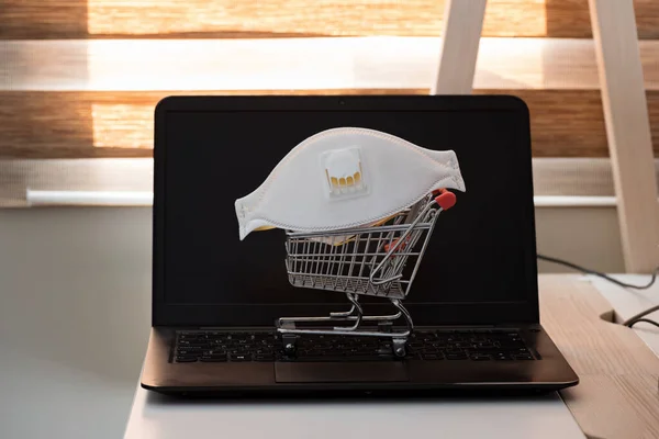 Konzeptfoto mit Miniatur-Einkaufswagen und Schutzmaske. Sicherheit beim Einkaufen im Internet — Stockfoto