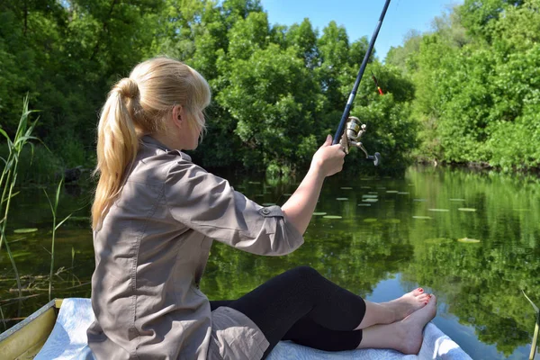 Menina em um barco está pescando no lago — Fotografia de Stock