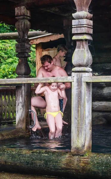 Der Mann badet das Mädchen in der heiligen Quelle. Bäder auf dem Hügel im Wald — Stockfoto
