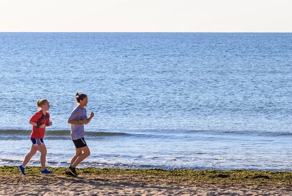 Twee meisjes rennen op het strand — Stockfoto
