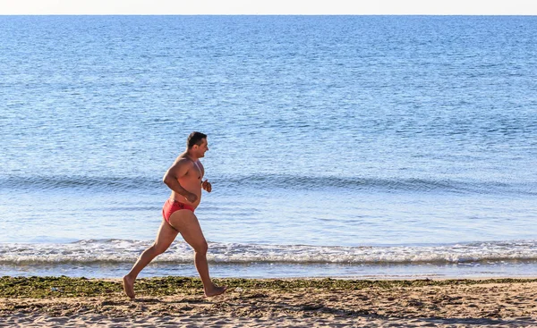 Sportlicher Mann läuft am Sandstrand — Stockfoto