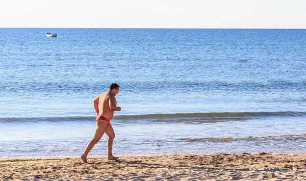 Uomo atletico che corre sulla spiaggia sabbiosa — Foto Stock