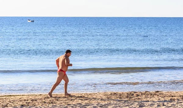 Kumsalda koşan atletik adam — Stok fotoğraf