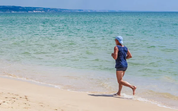 An elderly man runs along the seashore