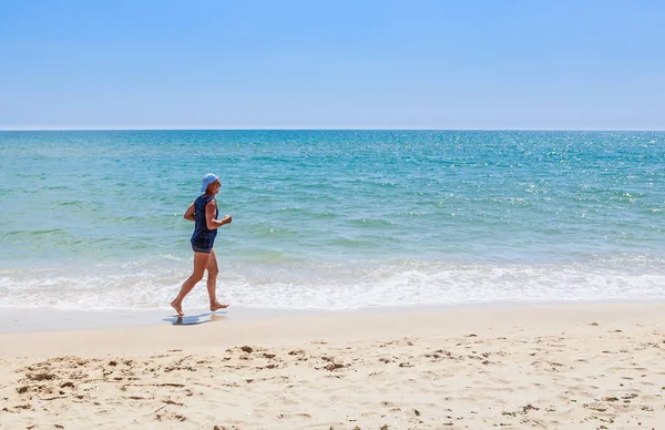 An elderly man runs along the seashore