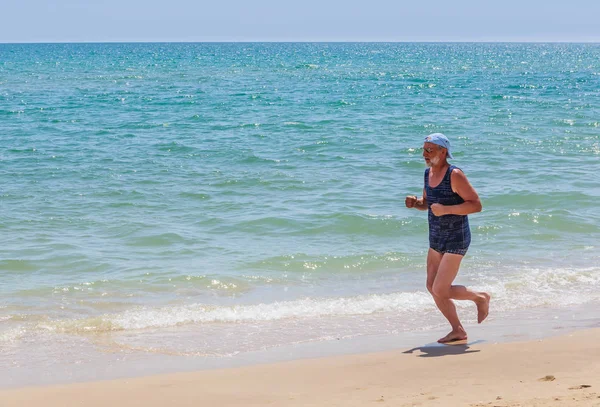 An elderly man runs along the seashore — Stock Photo, Image