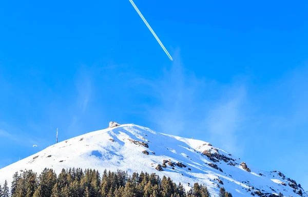 Flugzeug in einem blauen Himmel mit Spuren. Bergsalve im Winter — Stockfoto
