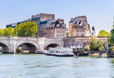 PARIS, FRANCE - MAY 11, 2017:  The Vedettes du Pont Neuf tour boat on the Seine River near a bridge. Equestrian statue of Henri IV. Paris, France clipart