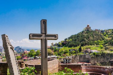 Aziz Niklas Kilisesi 'nin bahçesinde antik Narikalai Kalesi' nin bölgesinde haç ve levrek rahatlığı. Arka planda Tabor Dönüşüm Manastırı. Tiflis, Gürcistan