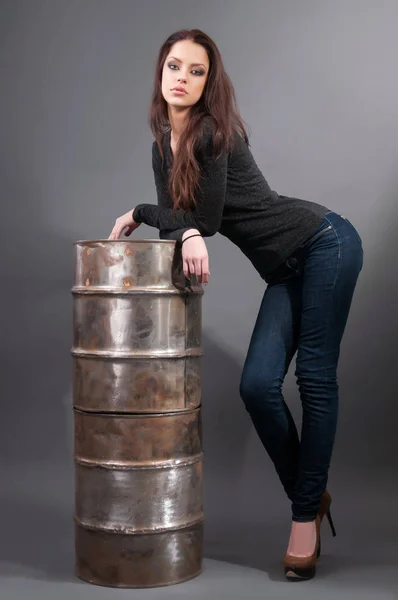 Dziewczyna w dżinsy, stojący w pobliżu baryłkę żelaza — Zdjęcie stockowe