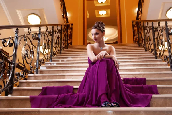 Donna in un abito lungo è seduto sulle scale — Foto Stock