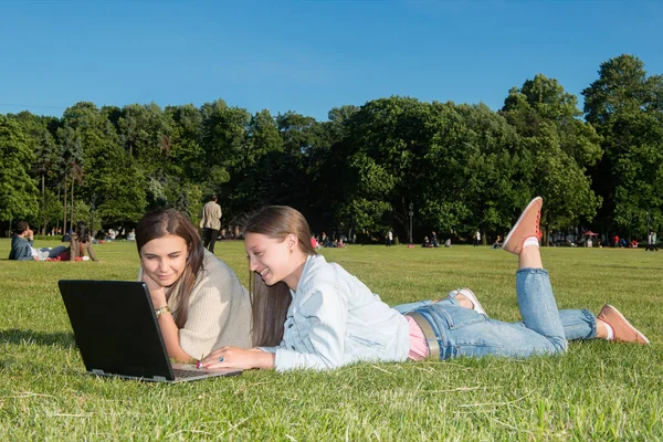 Dos chicas en el parque con un portátil — Foto de Stock