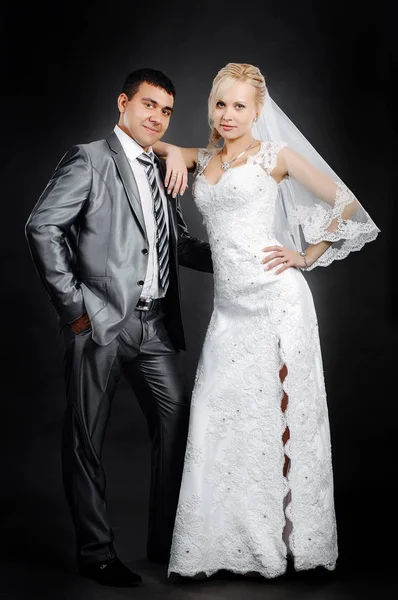 Milující novomanželé stojící na šedém pozadí — Stock fotografie