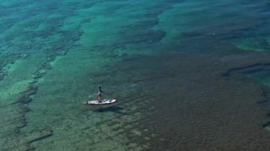 Mavi bir denizde Sup 'ta kürek çeken bir kadın..