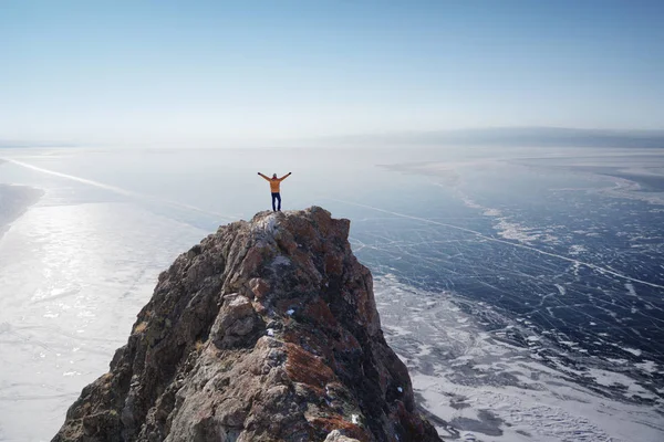 Lago Baikal en invierno. Hombre de pie en un acantilado y mirando el lago congelado Baikal . — Foto de Stock