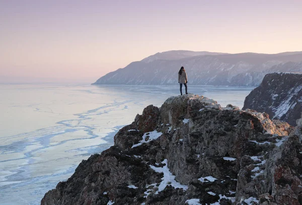Jezioro Bajkał w zimie. Kobieta stojąca na szczycie góry i gapiąca się na zamarznięte jezioro Baikal. — Zdjęcie stockowe