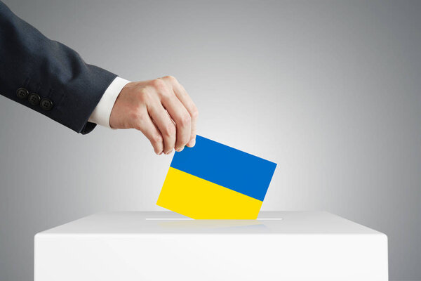 Man putting a ballot into a voting box.