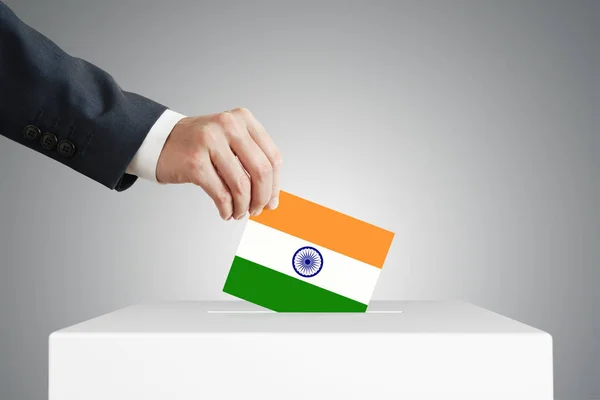 Man putting a voting ballot into a box with Indian flag.
