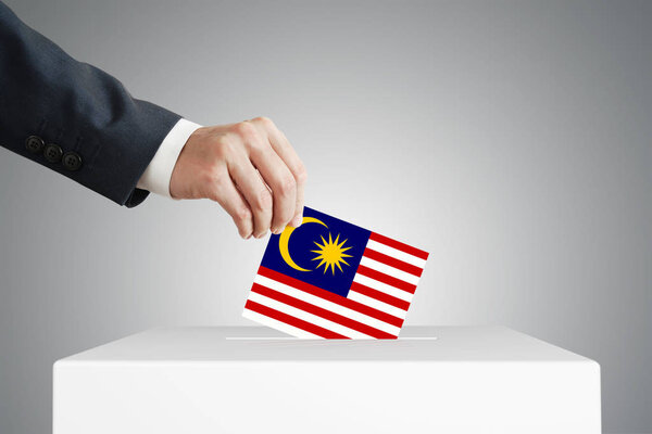 Человек, положивший бюллетень для голосования в ящик с флагом Малайзии
.