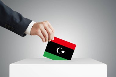 Libya bayrağı taşıyan bir sandığa oy veren adam.