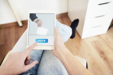 Çevrimiçi Oy Veren Adam Dijital Tablet Kullanarak Evde Oturuyor.