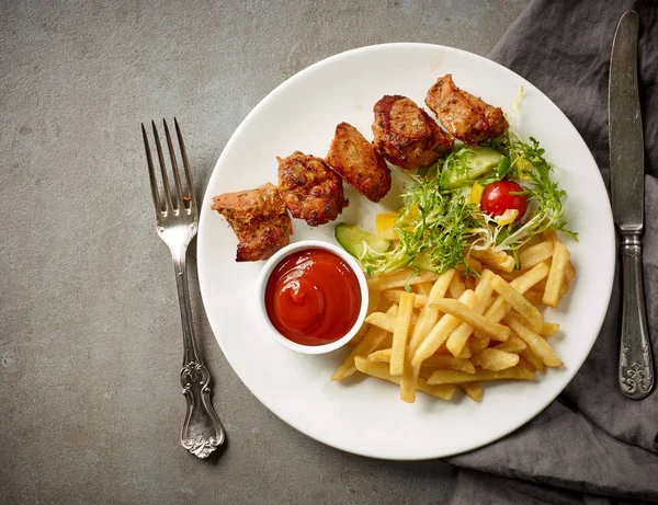 Plate of fried potatoes and pork kebab — Stock Photo, Image