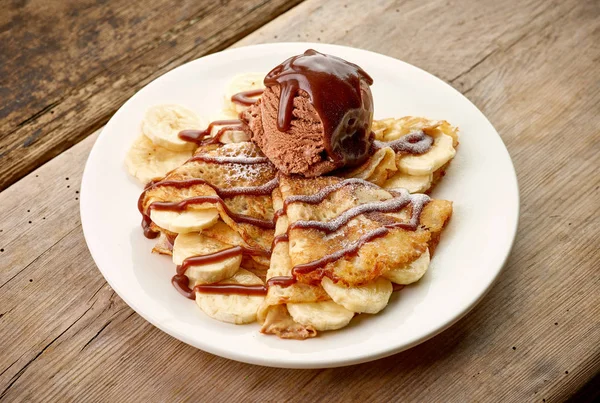 Pannenkoeken met banaan en chocolade ijs op houten bureau — Stockfoto