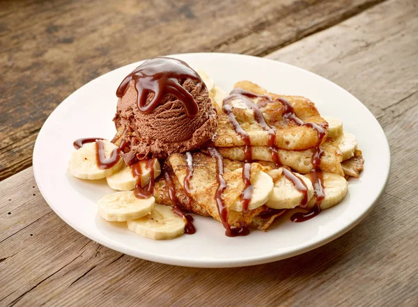 Crêpes mit Banane und Schokoladeneis auf Holztisch — Stockfoto