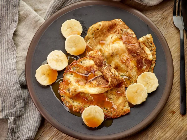 Crepes con plátano y salsa de caramelo en escritorio de madera —  Fotos de Stock