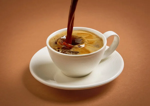 茶色の背景にコーヒーを注ぐカップ — ストック写真
