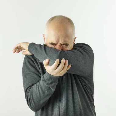 Beyaz arka planda bir dirsek içinde öksüren son sınıf öğrencisi.