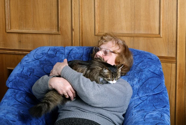 Stara kobieta na krześle w uścisku z kotem — Zdjęcie stockowe