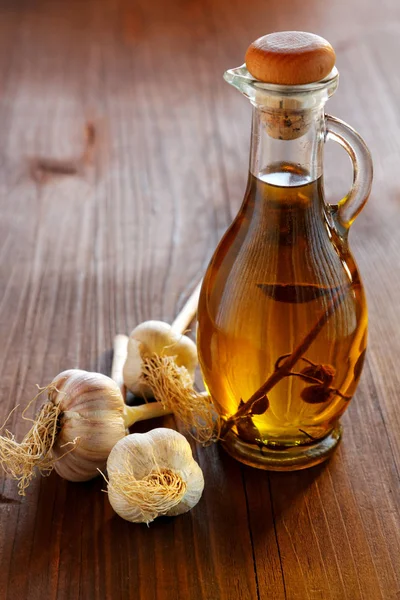Голова пляшки часнику та оливкової олії на сільському столі — стокове фото