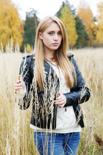 穿一件皮夹克黄色的草丛中的女孩 — 图库照片