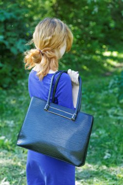 Bir yaz gününde ağaçları arasında bir çanta ile kız